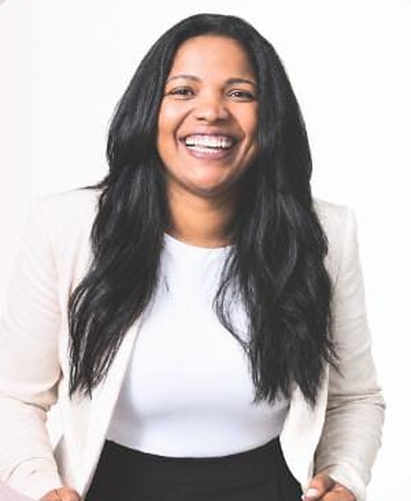 Pastora Géssica Abreu sorrindo, com cabelo longo e escuro, blusa branca e blazer claro.